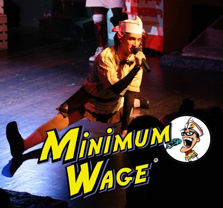 Minimum Wage — a performer in a burger-joint uniform mid-song on stage